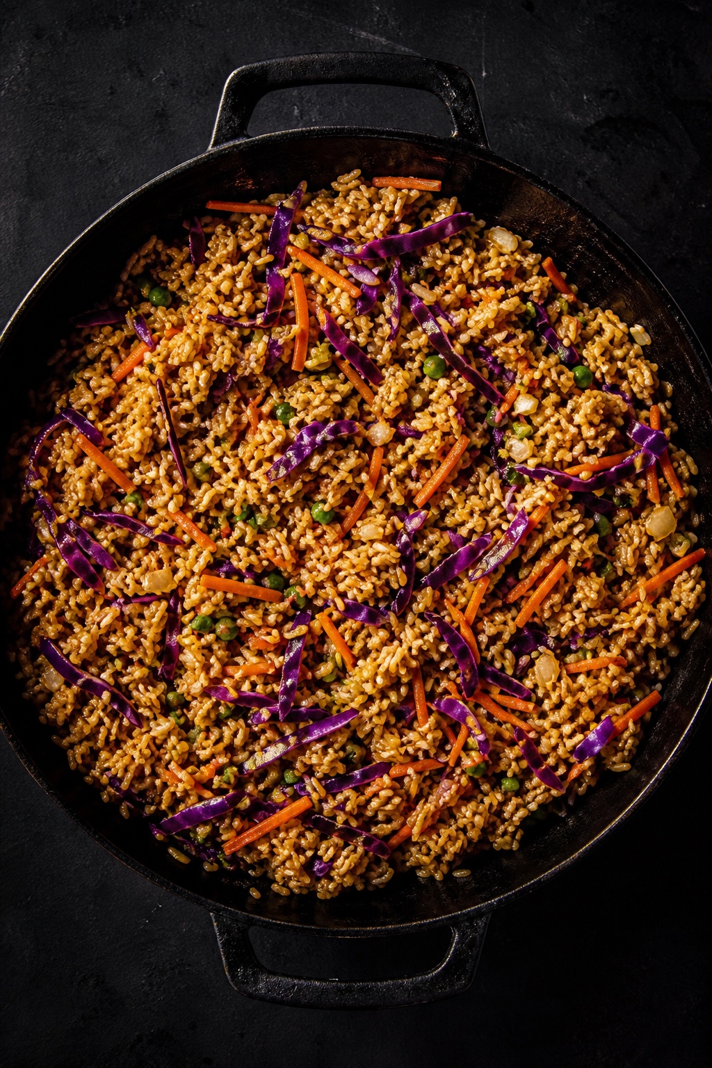 Veggie fried rice with shredded purple cabbage and carrot, overhead flat-lay in a dark pan, vegetarian